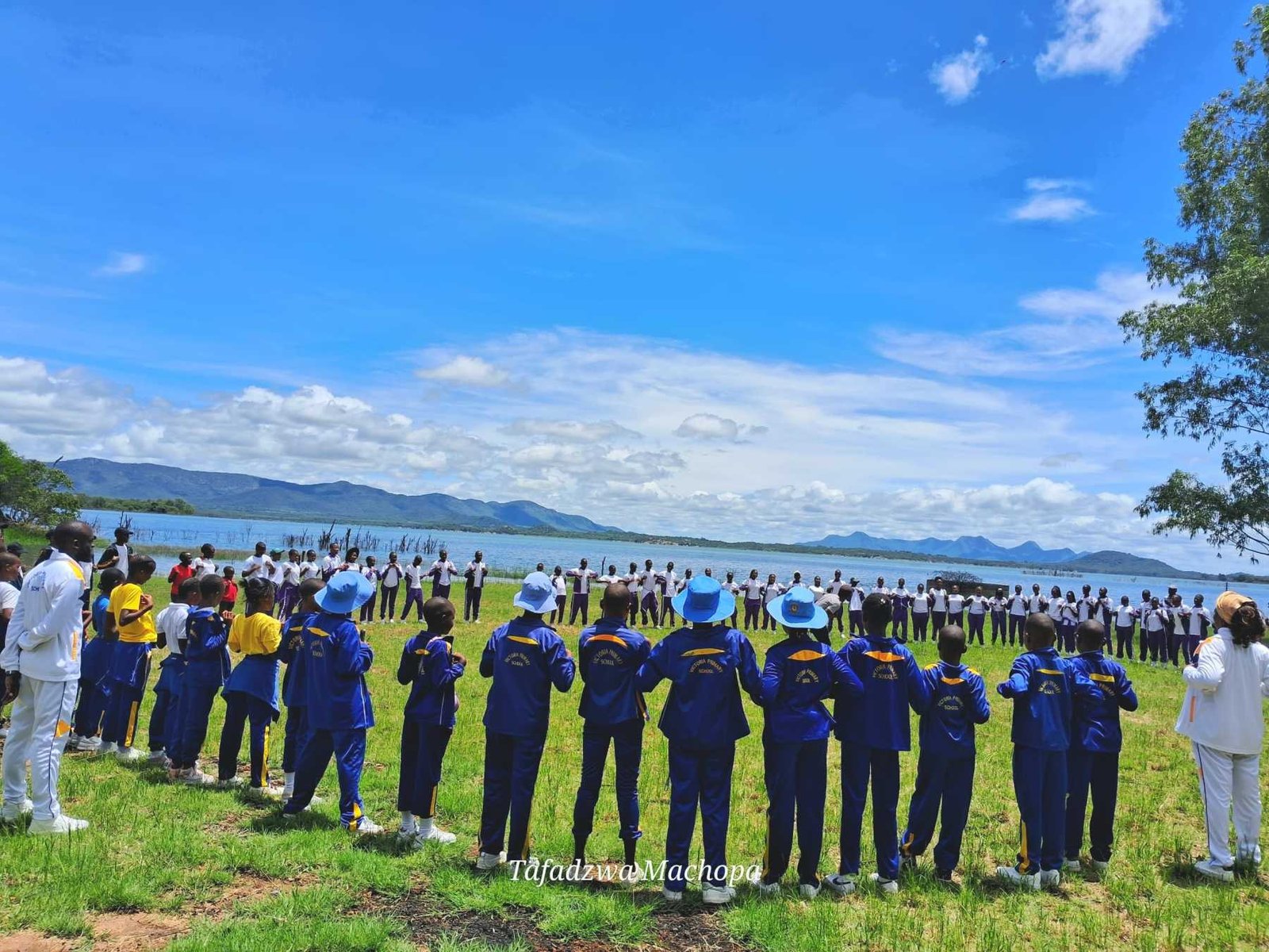 A large group gathered on the lawn beside the lake for a team-building day
